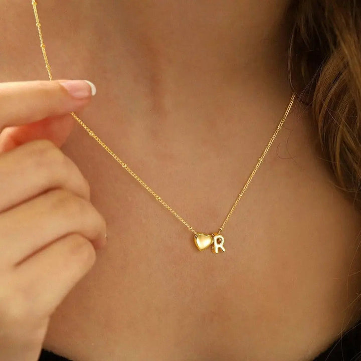 Heart initial necklace styled on a neck
