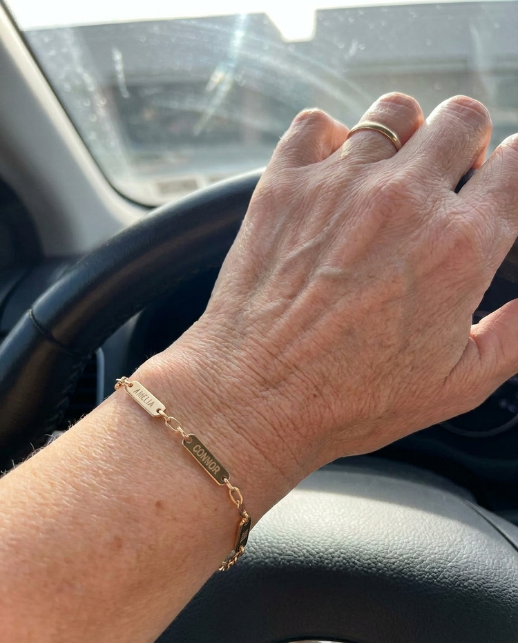 Customer wearing an engraved bar name bracelet in gold