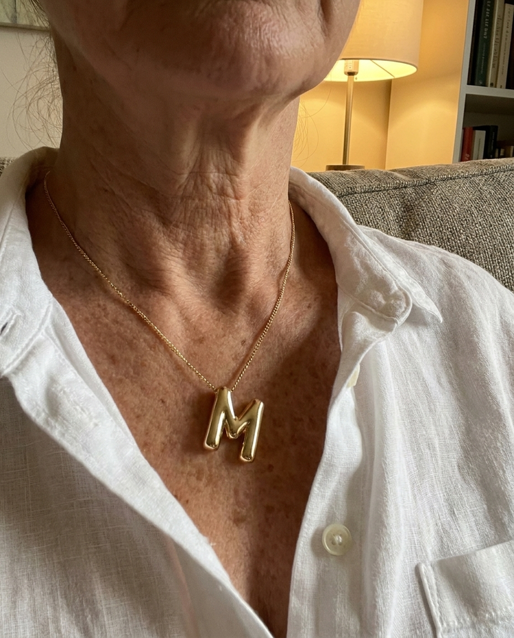 Customer wearing a bubble initial necklace in gold