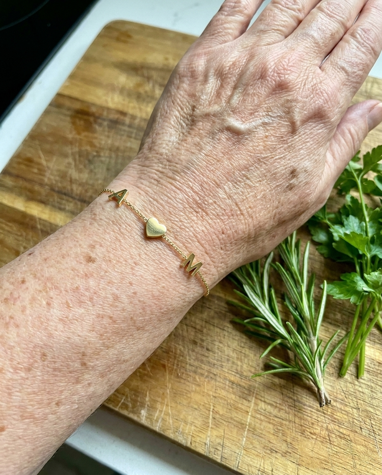 Customer wearing an initial and heart bracelet in gold